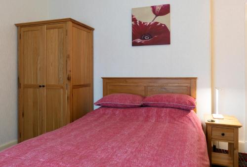 埃尔金Heather Glen Guest House的一间卧室配有一张带粉红色棉被的床