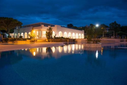 塔兰托Mon Rêve Resort的一座在晚上有大水池的建筑