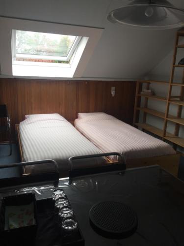 阿尔克马尔Cozy room in residential Alkmaar的配有书桌和窗户的客房内的两张床