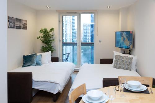 伦敦Royal Crossharbour Apartment的客厅配有两张床和一张餐桌