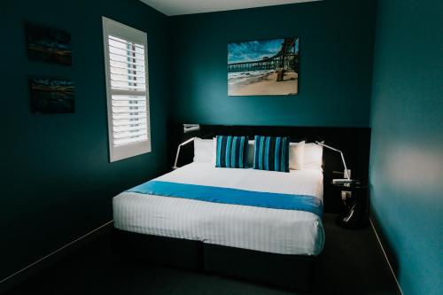 纽卡斯尔将克森酒店的一间卧室设有一张床和蓝色的墙壁
