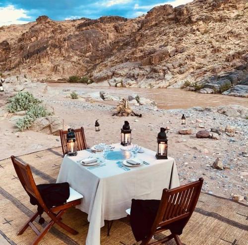 TissintAmoudou Lodge Camp的沙漠中的一张带椅子和灯的餐桌