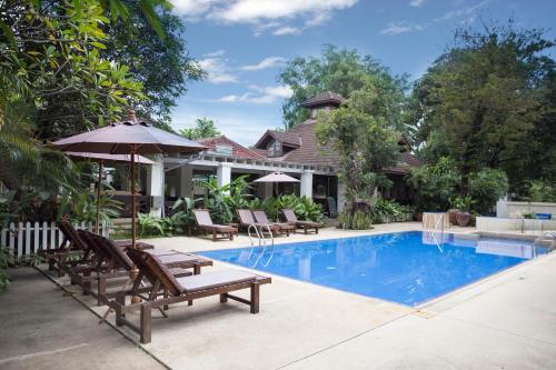清迈欧亚清迈酒店的房屋旁的游泳池配有椅子和遮阳伞