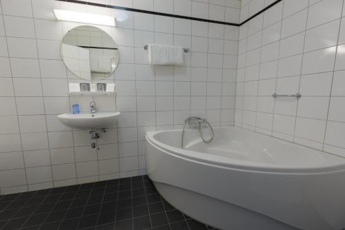 埃尔讷沃德普林斯霍夫酒店的白色瓷砖浴室设有浴缸和水槽