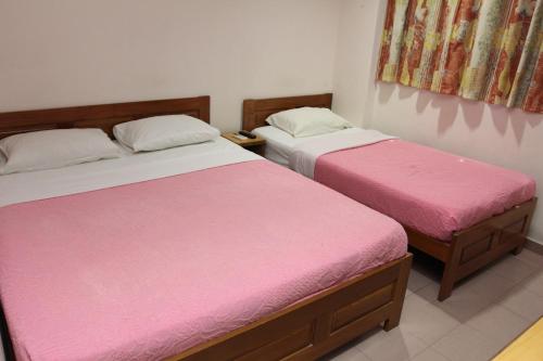 而连突小镇旅馆酒店的配有粉红色床单的客房内的两张床