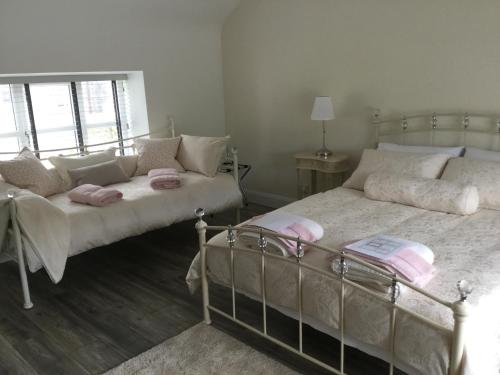 MultyfarnhamThe Stone House, Multyfarnham的一间卧室配有两张带粉红色枕头的床