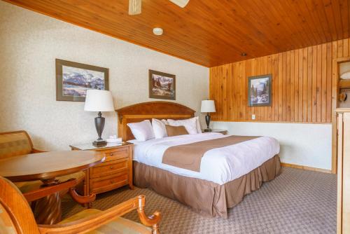 萨斯喀彻温河渡口可若酒店的一间卧室配有一张床、一张桌子和一张桌子
