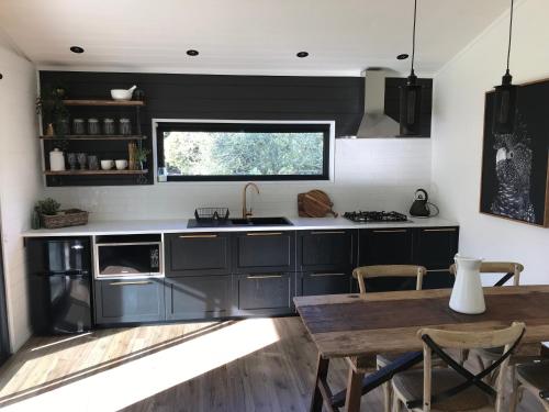 Nicholls RivuletThe Retreat的厨房配有黑色橱柜、桌子和窗户。