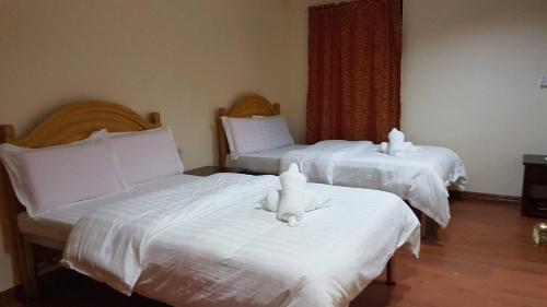 巴旺Hotel 45 Beach Resort的两张带白色床单和填充动物的床