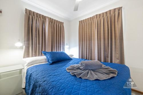 珀斯中央卡拉万假日公园的一间卧室配有一张带蓝色床单的床和一扇窗户。