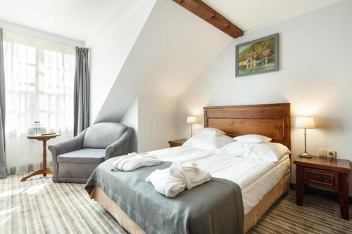 斯武普斯克多琳娜夏洛特Spa度假村的一间卧室配有一张带白色床单和椅子的床