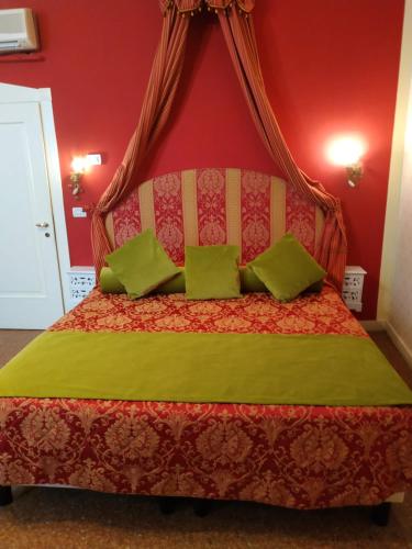 威尼斯Alloggi Acquavita - checkin at "Alloggi SS Giovanni e Paolo"的红色卧室配有带绿色枕头的床