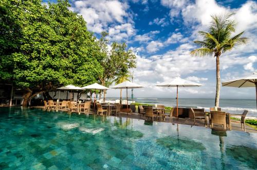 库塔巴厘岛花园海滩假日酒店的一个带椅子和遮阳伞的游泳池以及大海