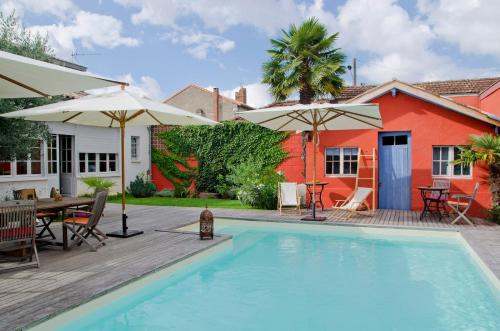 贝格莱La Ferrade Chambres d'Hôtes B&B的房屋旁的游泳池配有桌子和遮阳伞