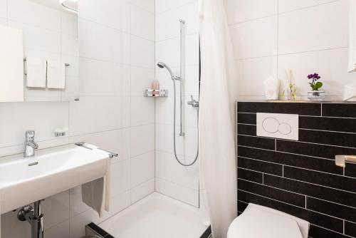 RütiNoah Hotel的带淋浴和盥洗盆的白色浴室