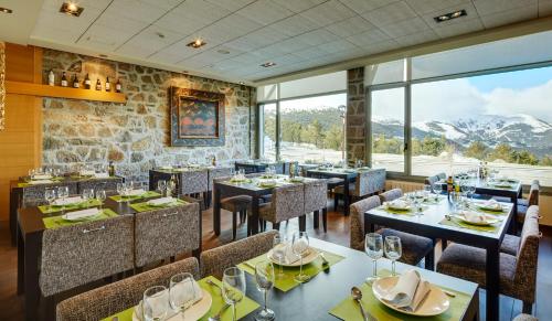 托瑟斯Hotel & Spa La Collada的餐厅配有桌椅,位于山脉的背景中