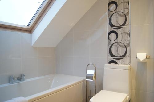 格拉斯哥Modern, Cosy Apartment In Bearsden with Private Parking的带浴缸、卫生间和窗户的浴室