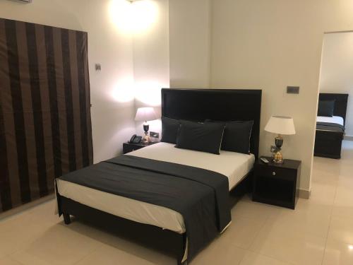 卡拉奇Sunset Suites的一间卧室设有一张大床和两个床头柜