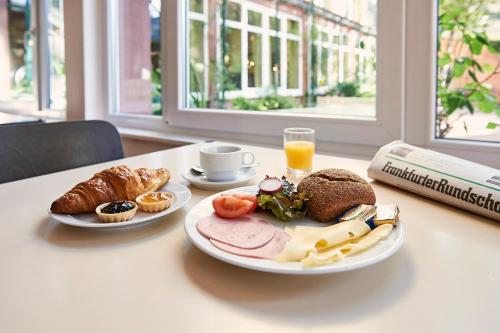 美因河畔法兰克福加戈黑保法兰克福-豪斯德加根德酒店的一张桌子,上面放着两盘食物和一杯橙汁