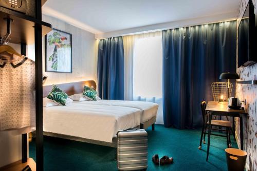 德希内斯·尚皮埃KOPSTER Hotel Lyon Groupama Stadium的一间卧室配有一张带蓝色窗帘的床和一张桌子