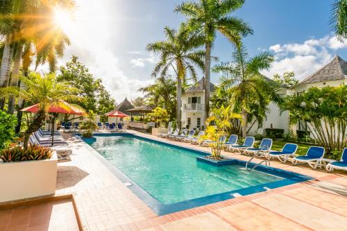 拉纳韦贝Decameron Club Caribbean Runaway Bay, Ramada All-Inclusive Resort的一个带椅子和棕榈树的度假村游泳池