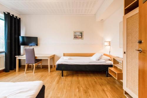 HolmsundVästerbacken Hotell & Konferens的酒店客房配有一张床、一张桌子和一把椅子。