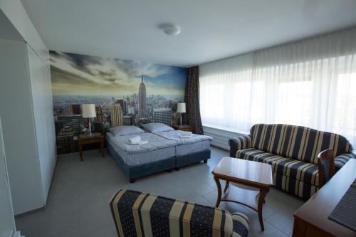 伍珀塔尔City Hotel Wuppertal的一间卧室配有一张床,客厅配有沙发