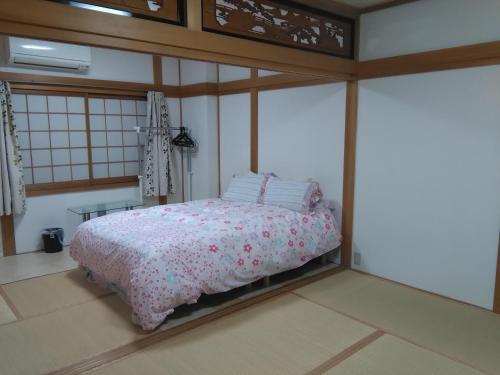 大阪大阪库马楼旅馆的一间卧室配有一张带粉红色棉被的床