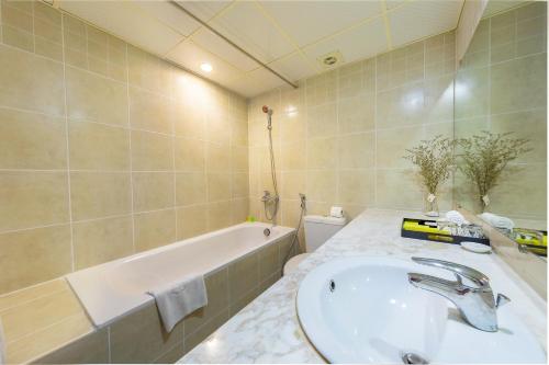 河内La Dolce Vita Hotel的浴室配有盥洗盆和浴缸。