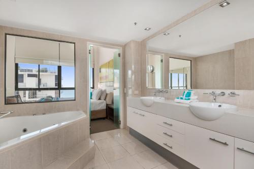 穆卢拉巴第一大道海标酒店的浴室设有2个水槽、浴缸和镜子