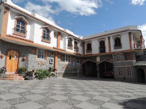 TambilloHostal Ñuca Huasi的一座大型建筑,设有一座石头庭院和一座建筑