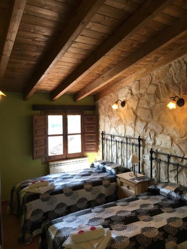 CastronuñoALTO DE LA RESERVA的一间卧室设有两张床和石墙