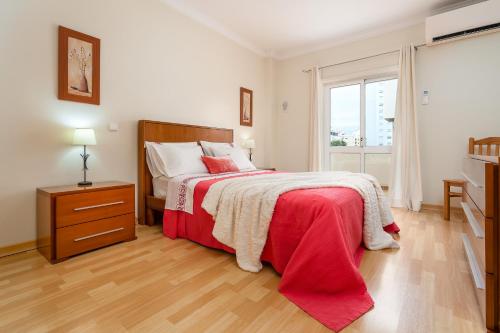 波尔蒂芒Cozy Apartment PORTIMÃO City Center的一间卧室配有一张带红色毯子的床和窗户。