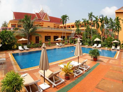 暹粒吴哥酒店的度假村的游泳池,配有椅子和遮阳伞