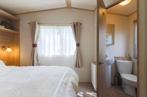帕兹托Blenheim, Padstow的一间卧室设有一张床、一个卫生间和一个窗口
