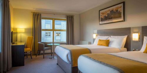 利默里克利姆瑞克玛尔德文酒店及休闲中心的酒店客房设有两张床和一张桌子。