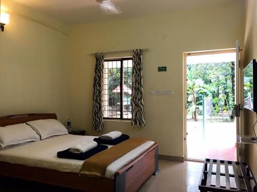 科钦棕榈树林服务式别墅酒店的一间卧室设有一张床和一个大窗户
