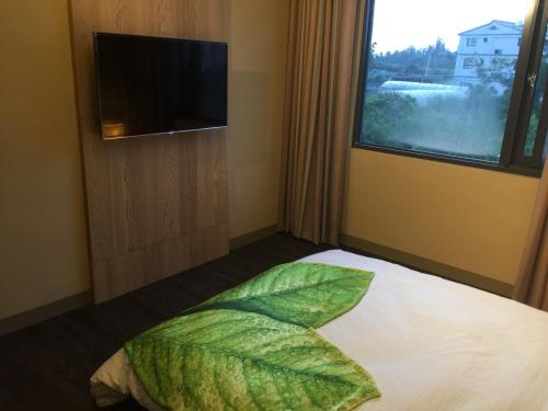 金宁乡三元民宿 的一间卧室配有一张带叶枕的床和窗户