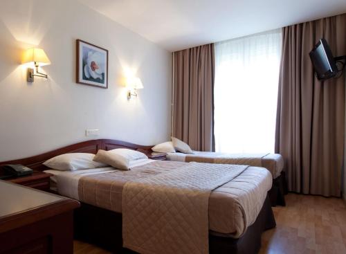 巴黎科斯莫特尔酒店的酒店客房设有两张床和窗户。