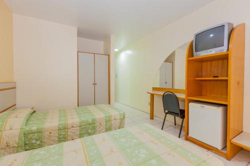弗洛里亚诺波利斯Tri Hotel Florianópolis的一间卧室配有一张床、一台电视和一张书桌