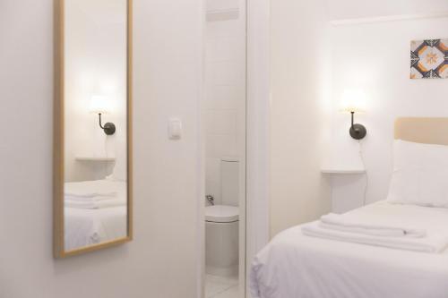埃武拉Casa Candeias的白色的客房配有床和镜子