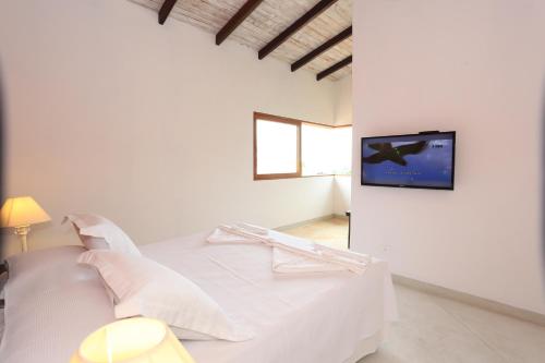伊利亚贝拉Chalés Mariolinha的白色的卧室设有床铺和墙上的电视