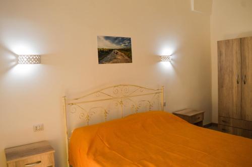 莱韦拉诺Borgo Greci的一间卧室配有带橙色床单和2盏灯的床。