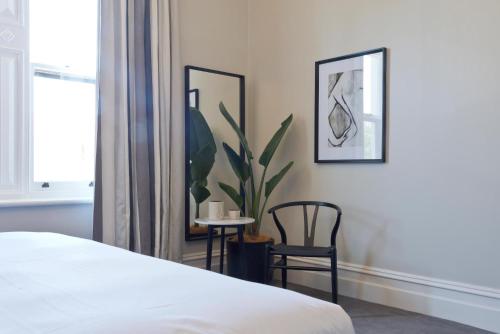 塔南达Villa Maria Barossa Luxury Guesthouse的一间卧室配有床和两把椅子以及植物