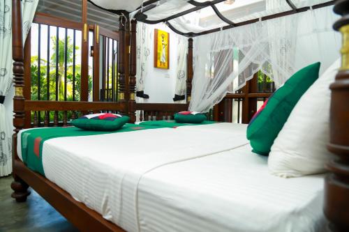 坦加拉Goyambokka Guesthouse的一间卧室配有带绿色和白色枕头的床