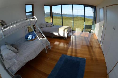 South BrunyMures Cloudy Bay Retreat的一间卧室设有两张床和大窗户
