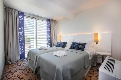 希贝尼克Amadria Park Ivan的酒店客房设有两张床和窗户。