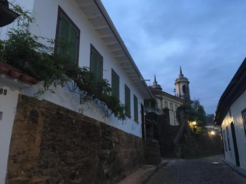 欧鲁普雷图Pouso Jardim de Assis的一座带绿色窗户的建筑和一座带钟楼建筑