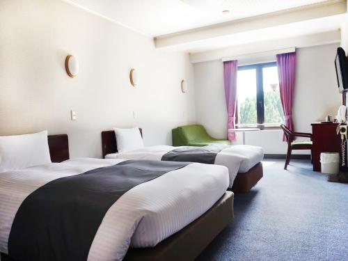 白马村艾贝斯特阿尔迪亚酒店的酒店客房设有三张床和窗户。