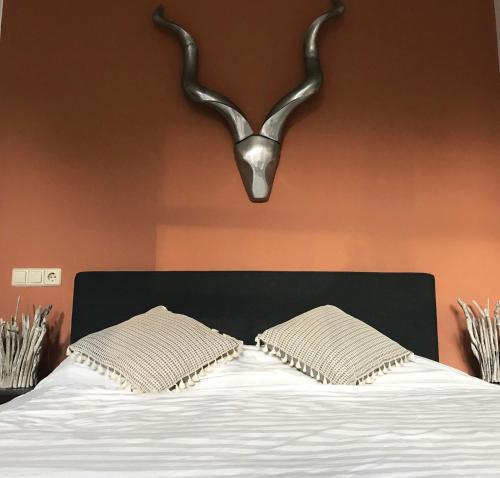 莱顿De Pelgrimsplaats的一间卧室配有一张带两个枕头的床和羚羊床头板